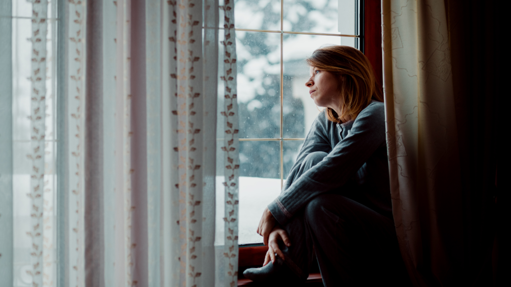 A woman sitting by the window, reflecting during a difficult divorce.
